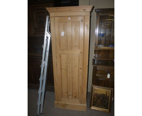 A modern narrow Victorian style pine wardrobe with flared cornice, fitted a single panel door opening to reveal hanging space