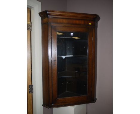 A 19th Century oak wall hanging corner cabinet with flared cornice and a single glaze panel door enclosing shaped shelves.