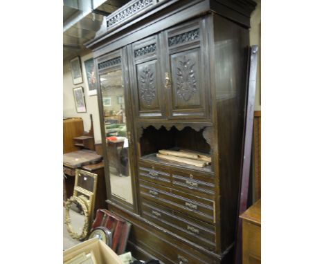 A Victorian carved and stained oak combination wardrobe with flared cornice, the left hand side with rectangular mirror panel