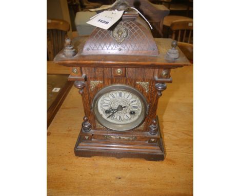 A 19th Century mantel clock in ornate oak case with decorative turned finials.