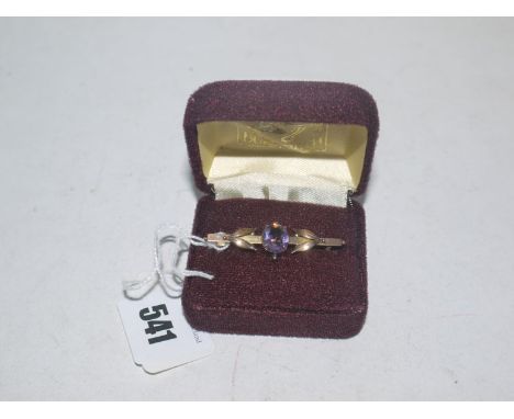 An amethyst set 9ct. yellow gold bar brooch, the oval facet cut amethyst claw set between leaves.