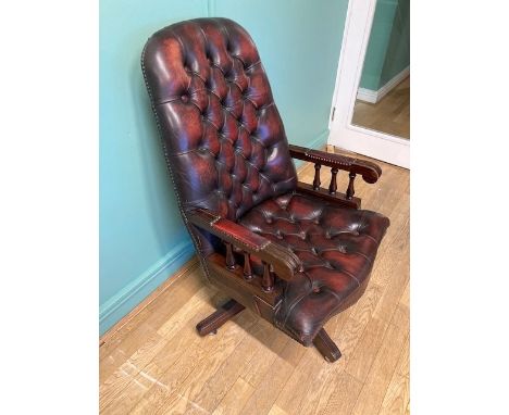 A mid 20th century brown leather Chesterfield swivel office armchair, button back and studded seat on four outswept legs with