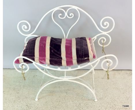 A wrought iron metal seat with striped cushion