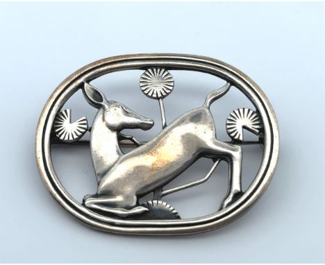 A Georg Jensen Danish oval pierced silver brooch with a deer kneeling amongst foliage. Designed by Arno Malinowski, pattern N
