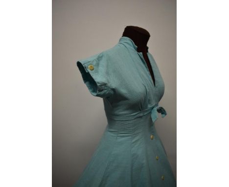 A 1950s textured cotton day dress in aqua blue, with faux buttons to front and cuffs and bow to under bust, full skirt and re