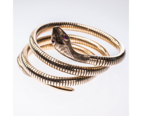 A 9CT YELLOW GOLD SNAKE BANGLE, the body coiled to create three bands, the head with engraved detailing and set with two ruby