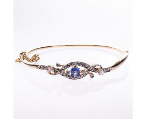 A LATE 19TH CENTURY SAPPHIRE AND DIAMOND BANGLE, the sapphire set within a scrolling cross over mount set throughout with old