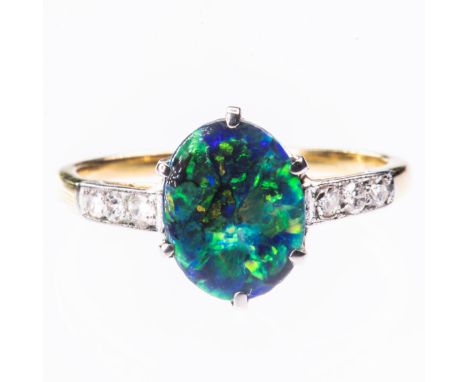 A BLACK OPAL AND DIAMOND RING, the oval cut opal set between open tapering shoulders set with diamond shoulders. Ring size M.