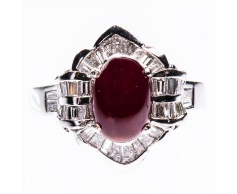 AN 18CT WHITE GOLD, RUBY AND DIAMOND RING, the oval cabochon cut ruby set within a structured surround with scalloped details