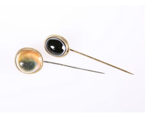 TWO TIGER'S EYE STICK PINS, LATE 19th CENTURY, each oval cabochon stone within a yellow metal mount, one cast with ropework (