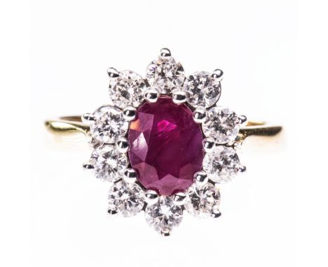 AN 18CT YELLOW GOLD, RUBY AND DIAMOND CLUSTER RING, the oval cut ruby set within a surround of ten brilliant cut diamonds on 