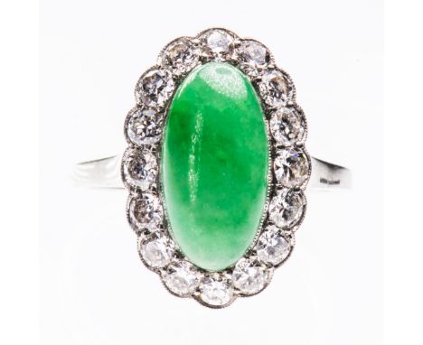 A JADE AND DIAMOND RING, the oval cabochon cut jade set within a scalloped edge mount of brilliant cut diamonds between pierc