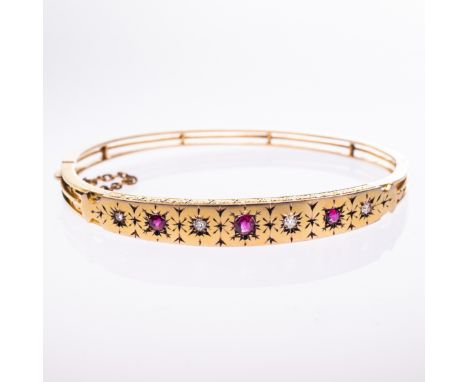 A MID 19TH CENTURY RUBY AND DIAMOND SET BANGLE, the tapering mount with engraved detailing set with three graduating rubies a