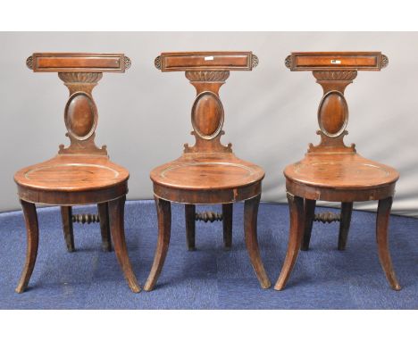 Three Georgian mahogany hall / footman's chairs with shaped seats, moulded splats and unusual narrowly spaced rear legs with 