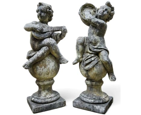 Architectural salvage - a near pair of reconstituted stone country house gatepost finials, of young musical putti, seated on 