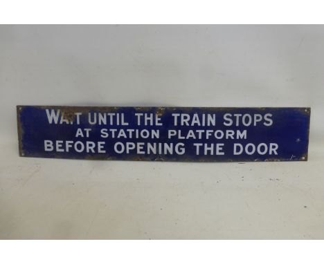 An early dark blue and white rectangular enamel sign - Wait Until The Train Stops at Station Platform Before Opening The Door