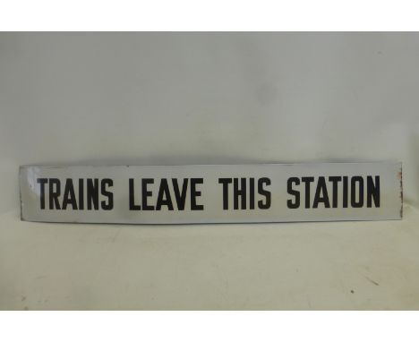 A rectangular black and white enamel sign - Trains Leave This Station, 43 1/2 x 6 1/2".
