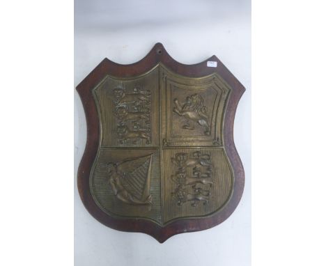 A shield shaped brass plaque, the design divided into four quarters, two with three lions, one with a prancing single lion an