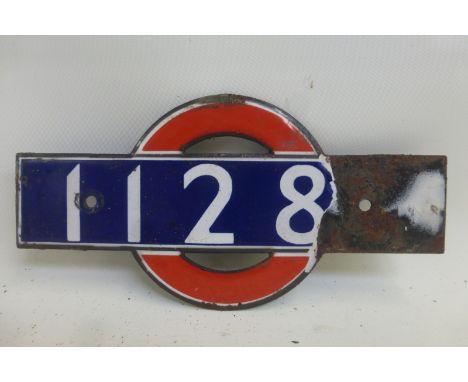 A small enamel plaque with red circle behind, no. 1128??, from a 1938 driving car.