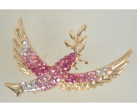 A vintage rhinestone set gold tone figural brooch in the form of a dove of peace carrying an olive branch with roller clip cl