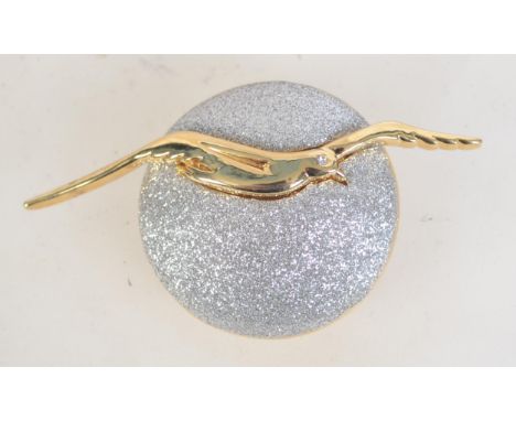 A vintage gold and silver tone figural brooch of a bird flying in front of the moon with roller clip clasp. Measures 7cms.