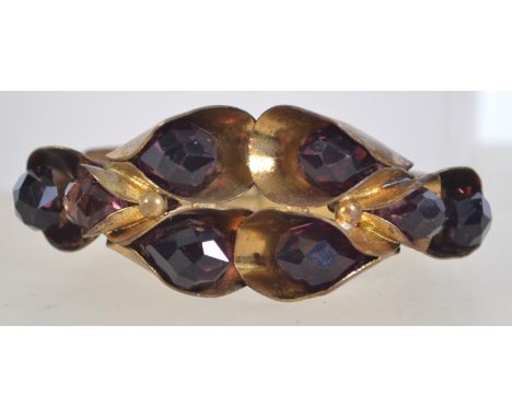 An Art Deco bangle clamper bracelet with Greek key decoration to band with large stylized lilies and faceted purple crystal b