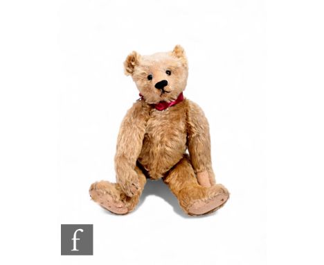 An early 20th Century mohair jointed teddy bear, possibly Farnell, straw filled with button eyes and humped back, length 50cm