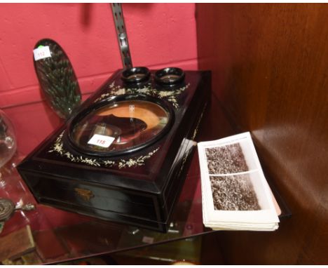 A Victorian stereoscopic viewer & slides, the hinged ebonised case decorated with floral sprays and inset with three magnifyi
