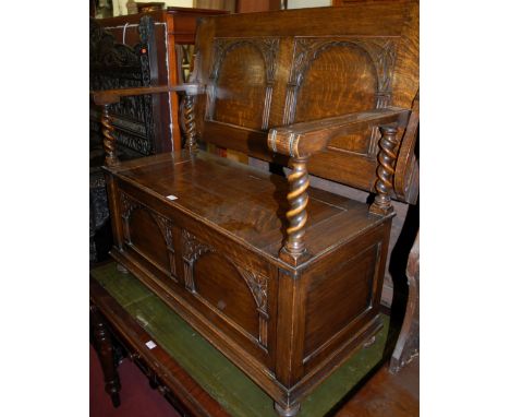 An early 20th century panelled oak fold-over monks, bench having barley twist columns and typical hinged box seat base, width