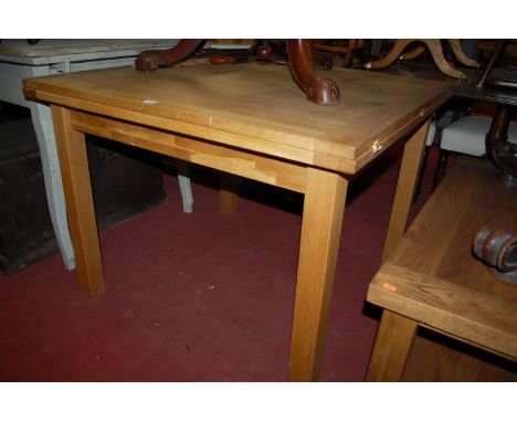 A contemporary light oak fold-over dining table having a revolving top