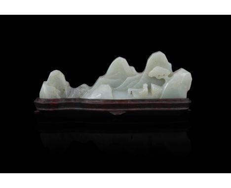 A Chinese celadon jade mountain-form brush rest, Qing Dynasty, carved with a scholar seated underneath a pine tree, the stone