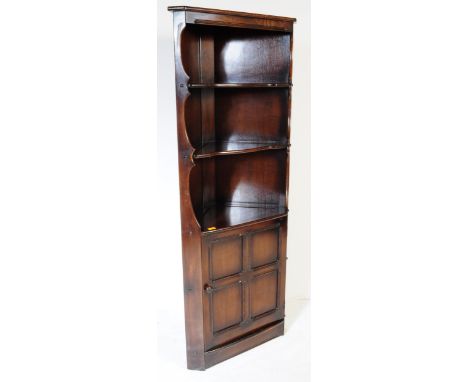 Ercol - Old Colonial - A 20th century Ercol Old Colonial elm corner cabinet unit having pediment top over shaped shelves over