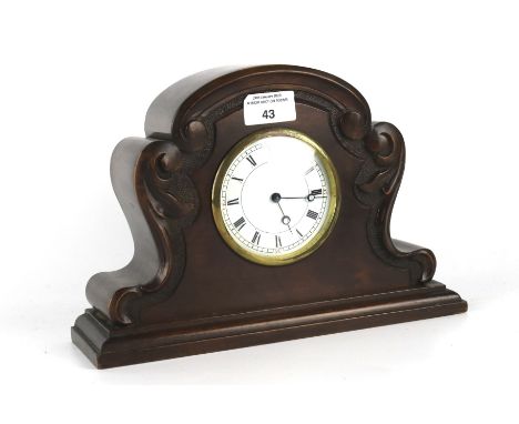 A Swiss Fontainemelon mantel clock. White dial with Roman numerals, in a carved wooden case raised on a plinth base, with pla