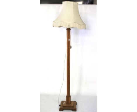 An Art Deco light oak standard lamp. Mounted onto a square base with square supports, with a cream shade, 151cm high (excludi