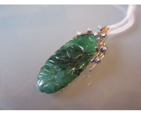 Carved green jade pendant in a white gold diamond set mount