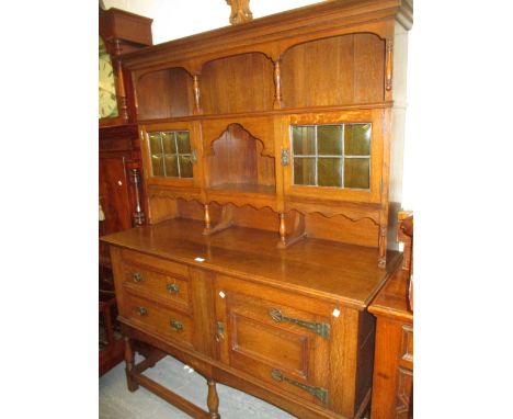 Arts and Crafts oak dresser with an open boarded shelf and leaded glass cupboard back above two drawers and a cupboard door w