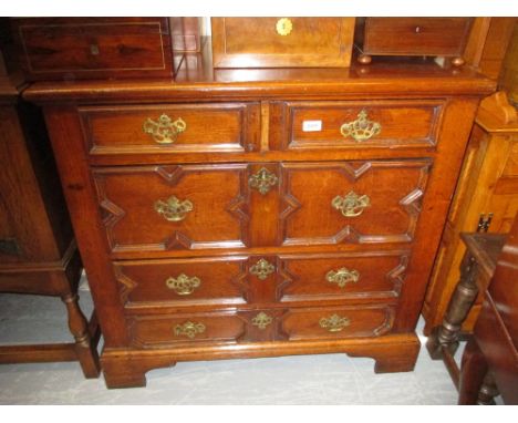 Oak Jacobean style straight front chest of four long moulded front drawers with brass handles and escutcheons raised on brack