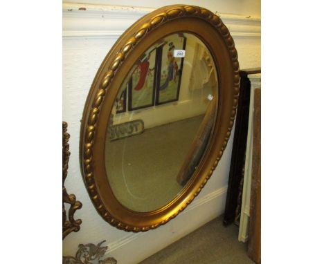 Oval gilt framed bevelled edge wall mirror together with an ebonised piano stool with revolving seat