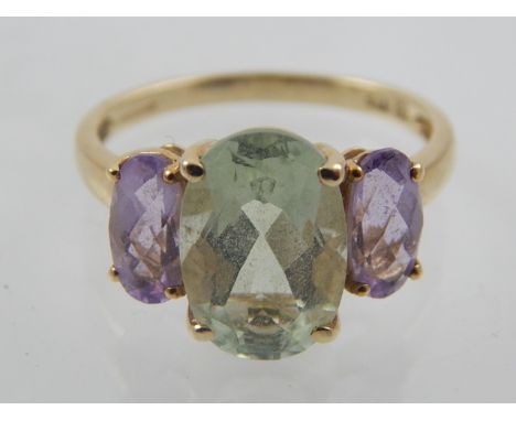 A 9 carat yellow gold, green amethyst (prasiolite) and purple amethyst ring, set central oval cut green amethyst flanked by t