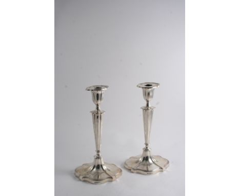 A PAIR OF EDWARDIAN CANDLESTICKS on shaped oval bases with tapering columns, reeded borders & detachable nozzles, each initia