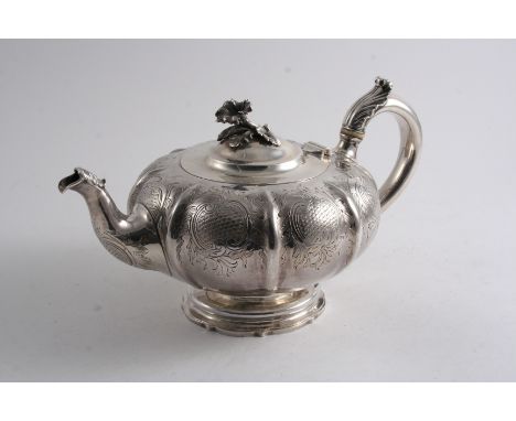 A VICTORIAN MELON-FLUTED TEA POT with chased decoration around the sides, a C-scroll handle & a flower finial, with a small i