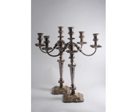 A PAIR OF PLATED THREE-LIGHT CANDELABRA on shaped square bases, with reeded scroll branches, (lacking detachable nozzles);  1