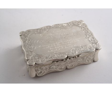 A VICTORIAN ENGRAVED SNUFF BOX of shaped oblong outline with concaved sides, a presentation inscription on the cover & gilt i
