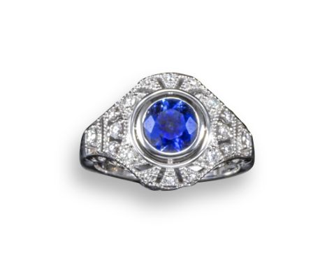 A sapphire and diamond cluster ring, rubover-set with a circular-cut sapphire weighing approximately 1.40cts within an openwo