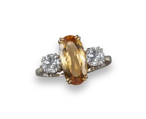 An orange topaz and diamond ring, the oval-shaped orange topaz set with two round brilliant-cut diamonds in yellow gold, size