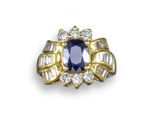 A sapphire and diamond cluster ring, the oval-shaped sapphire is set within a surround of circular-cut and channel-set tapere