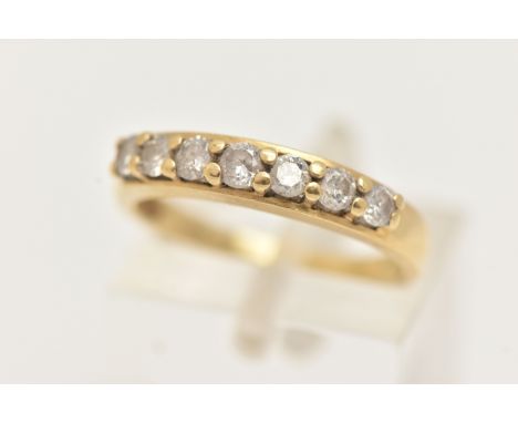 A YELLOW METAL DIAMOND SEVEN STONE RING, set with a row of seven round brilliant cut diamonds, each in a four claw setting, l