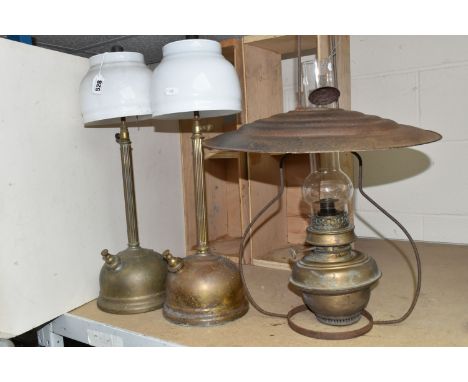 THREE BRASS PARAFIN LAMPS comprising two Tilley table lamps with glass shades, height 52cm and 55cm, a brass hanging paraffin