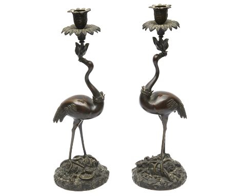 A pair of William IV patinated bronze candlesticks in the manner of Abbot &amp; Co cast in the from of a standing storks with