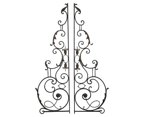 A pair of wrought iron garden gates, black painted, of scrollwork design, with gilt acanthus leaf, flamiform finials and flow